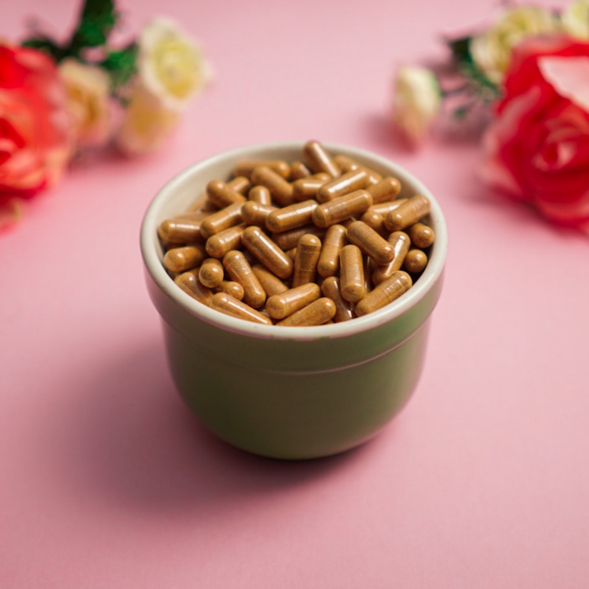 bowl of capsules with roses in background